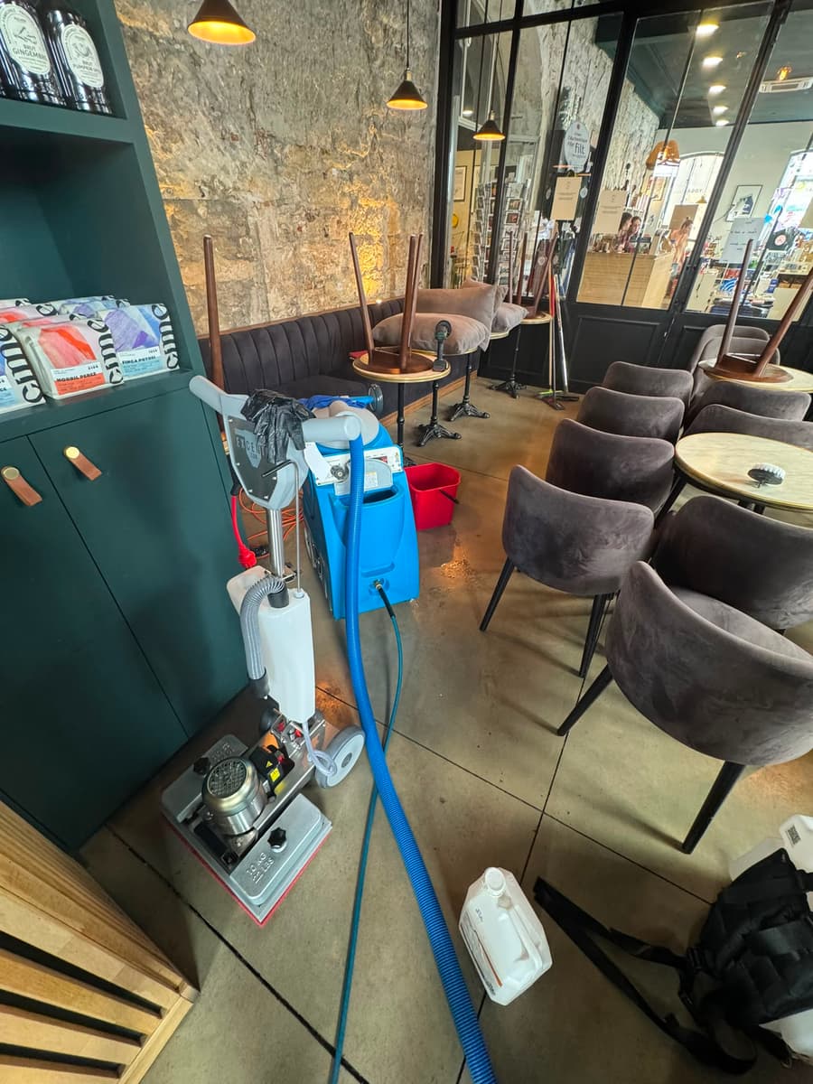 Injecteur-extracteur et seau installés dans un café, fauteuils taupe et mur de pierre