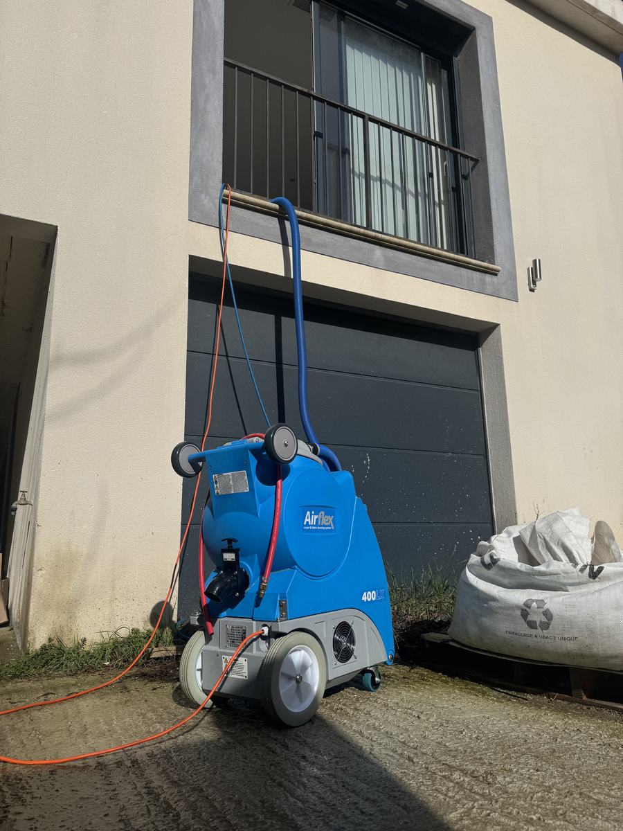 Injecteur-extracteur Airflex posé devant une maison, tuyaux déroulés jusqu’au véhicule