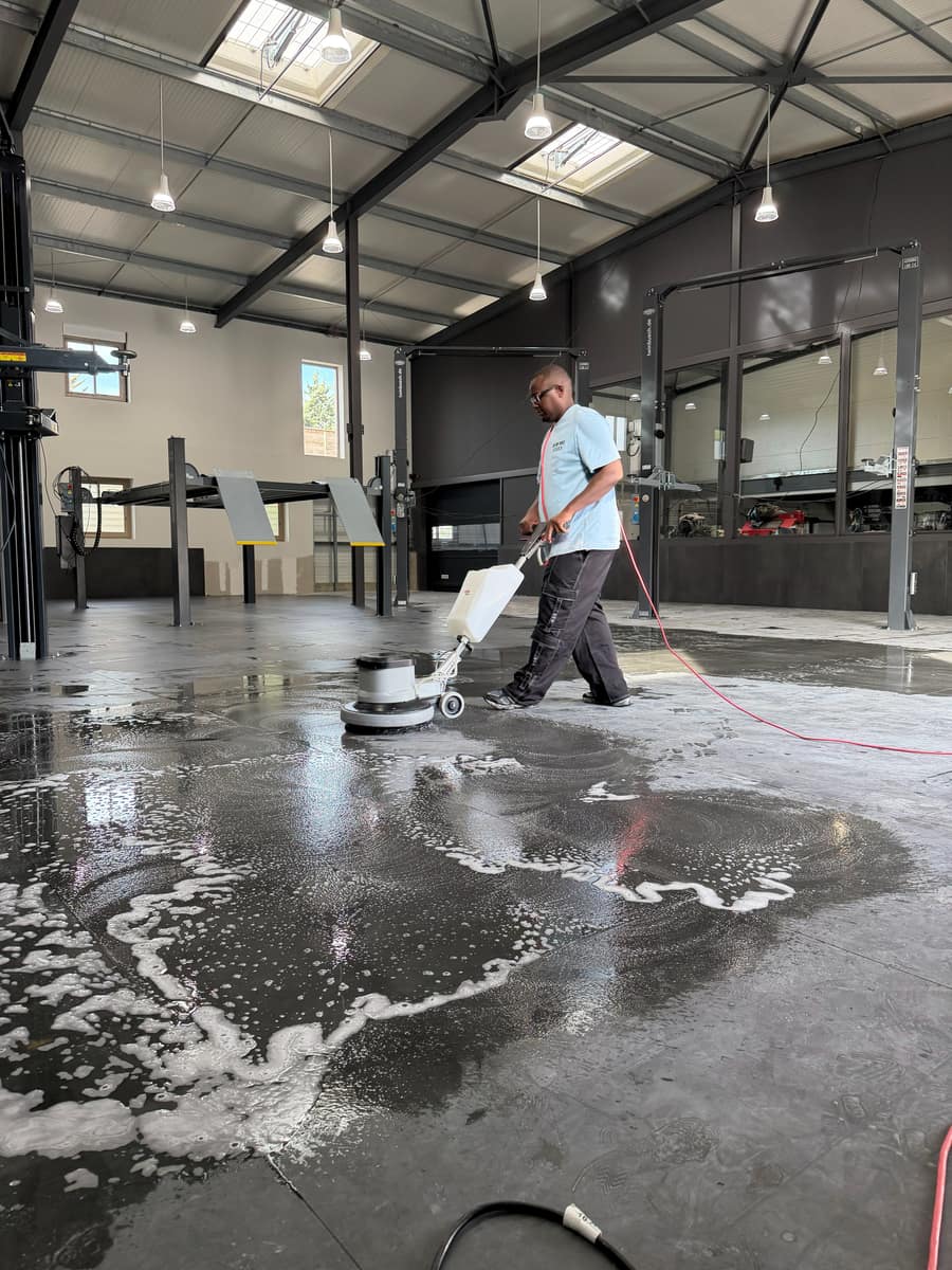 Soum passe la monobrosse sur le sol d'un hangar en fin de chantier, mousse et eau étalées au sol