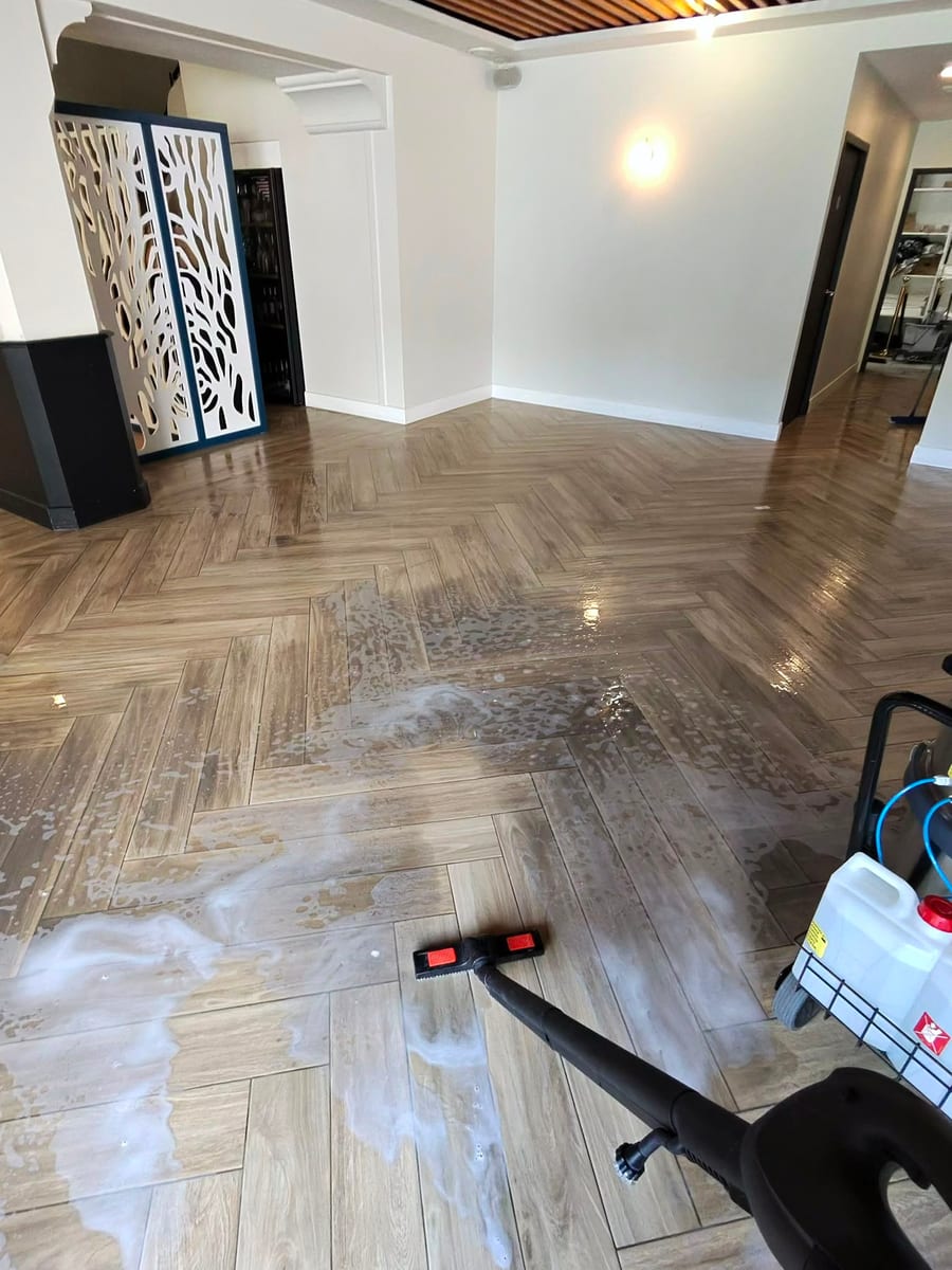 Parquet en chevrons en cours de lavage mécanique, eau au sol et machine au fond