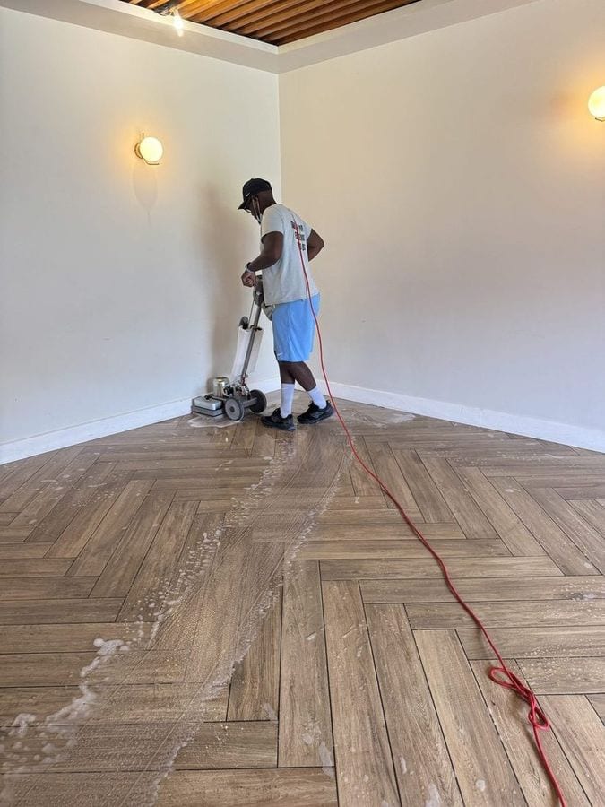Soum passe la monobrosse sur un parquet à chevrons dans une pièce vide et claire