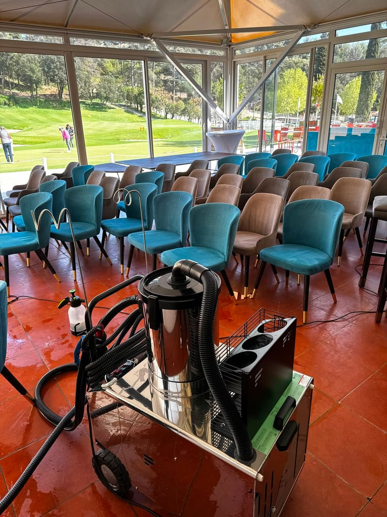 Salle de réception aux chaises en velours turquoise et beige, machine d'injection-extraction au premier plan