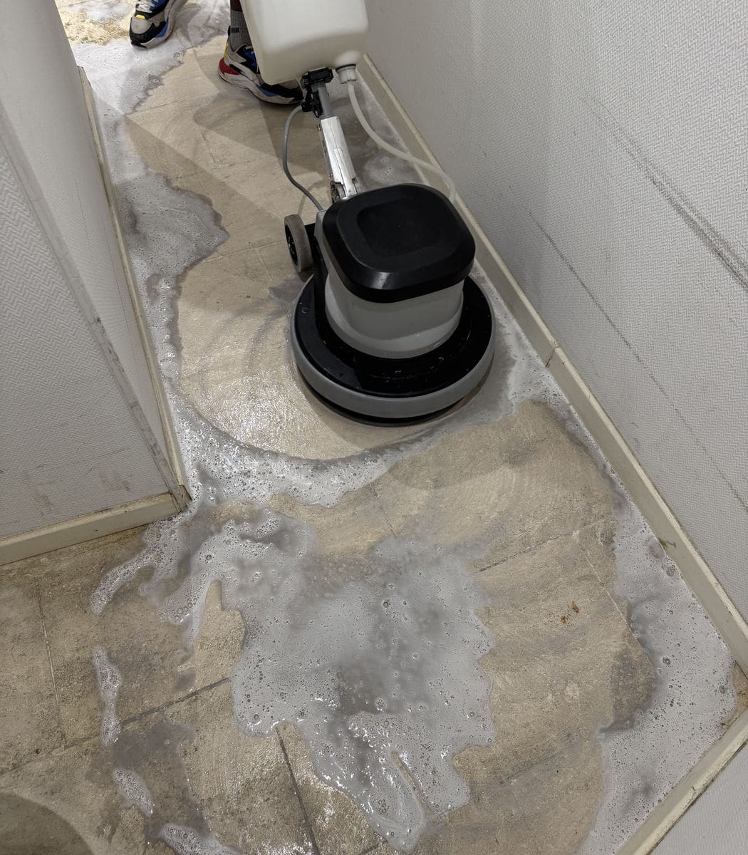 Monobrosse en action sur un sol carrelé fortement encrassé, mousse de nettoyage répandue dans un couloir