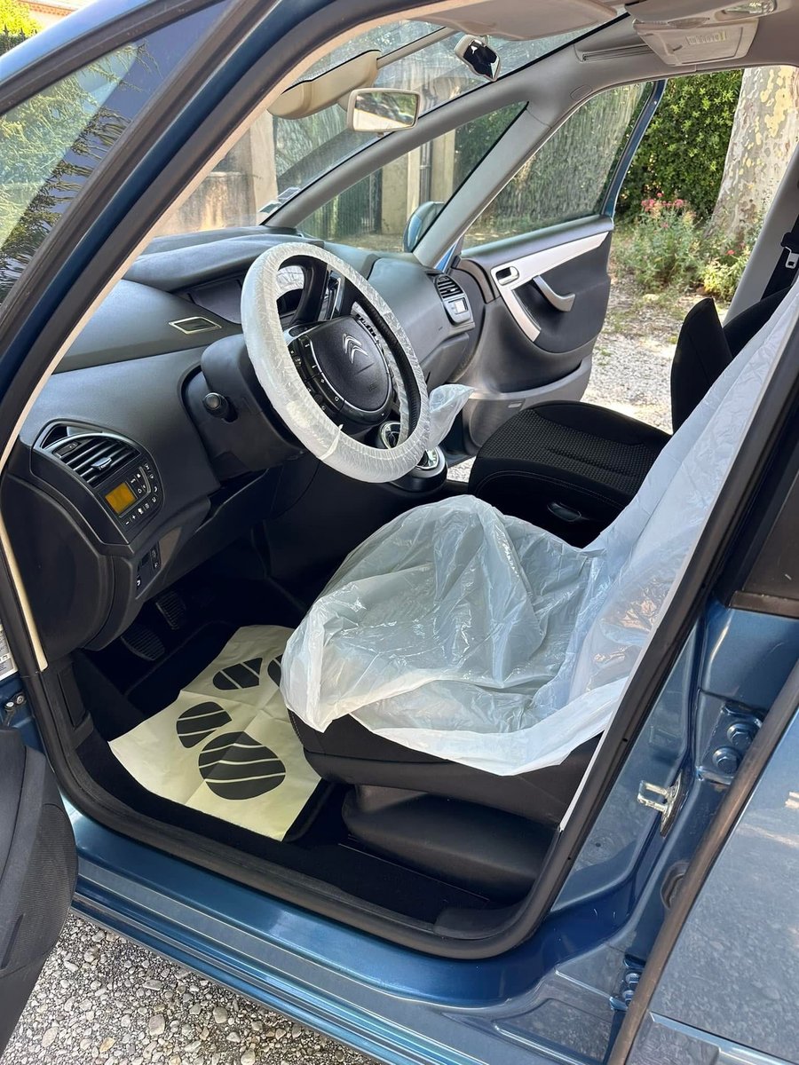 Poste de conduite protégé par une housse de siège et un tapis de sol jetables, volant sous film