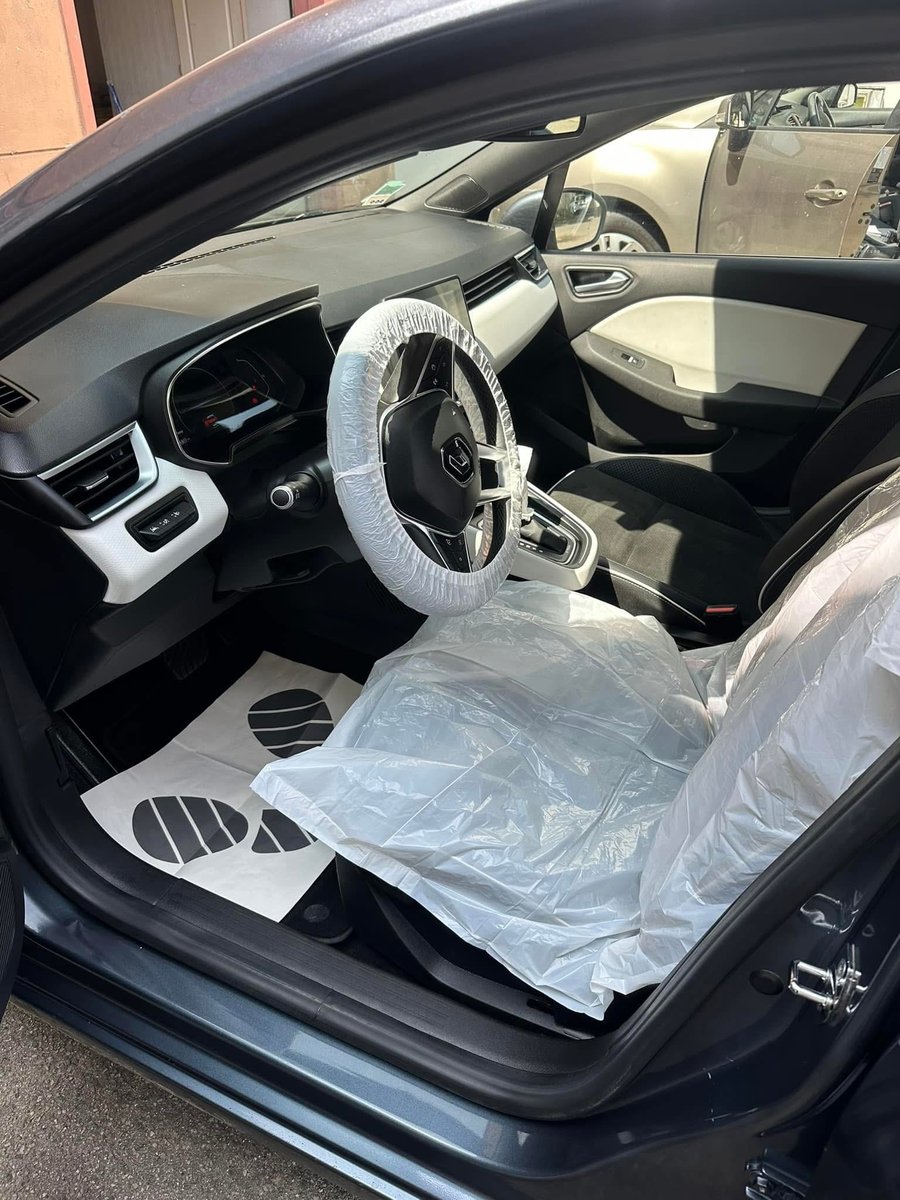 Poste de conduite d'une berline sous housse de siège plastique, volant protégé et tapis de sol jetable