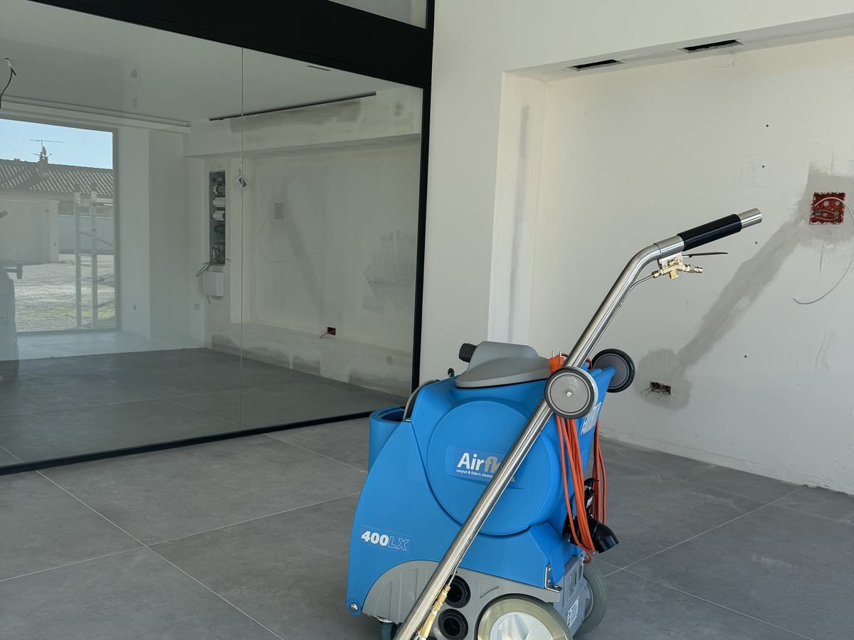 Machine d’injection-extraction posée devant une grande cloison vitrée dans une pièce blanche en fin de chantier