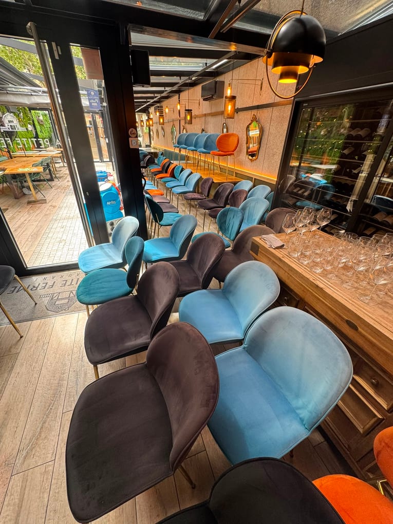 Rangées de chaises en velours bleu, brun et orange le long du comptoir d'un bar