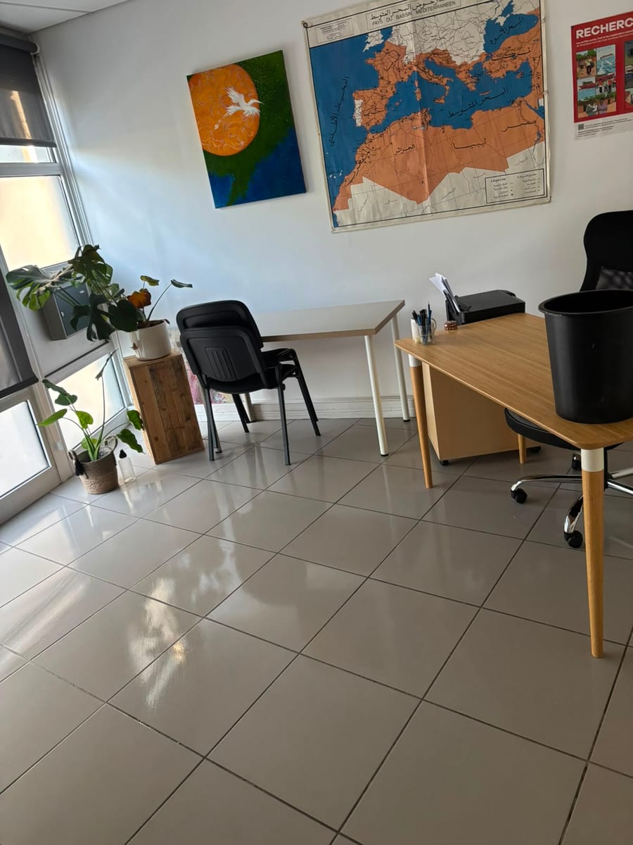 Bureau clair avec une carte murale et un tableau, sol carrelé brillant devant la baie