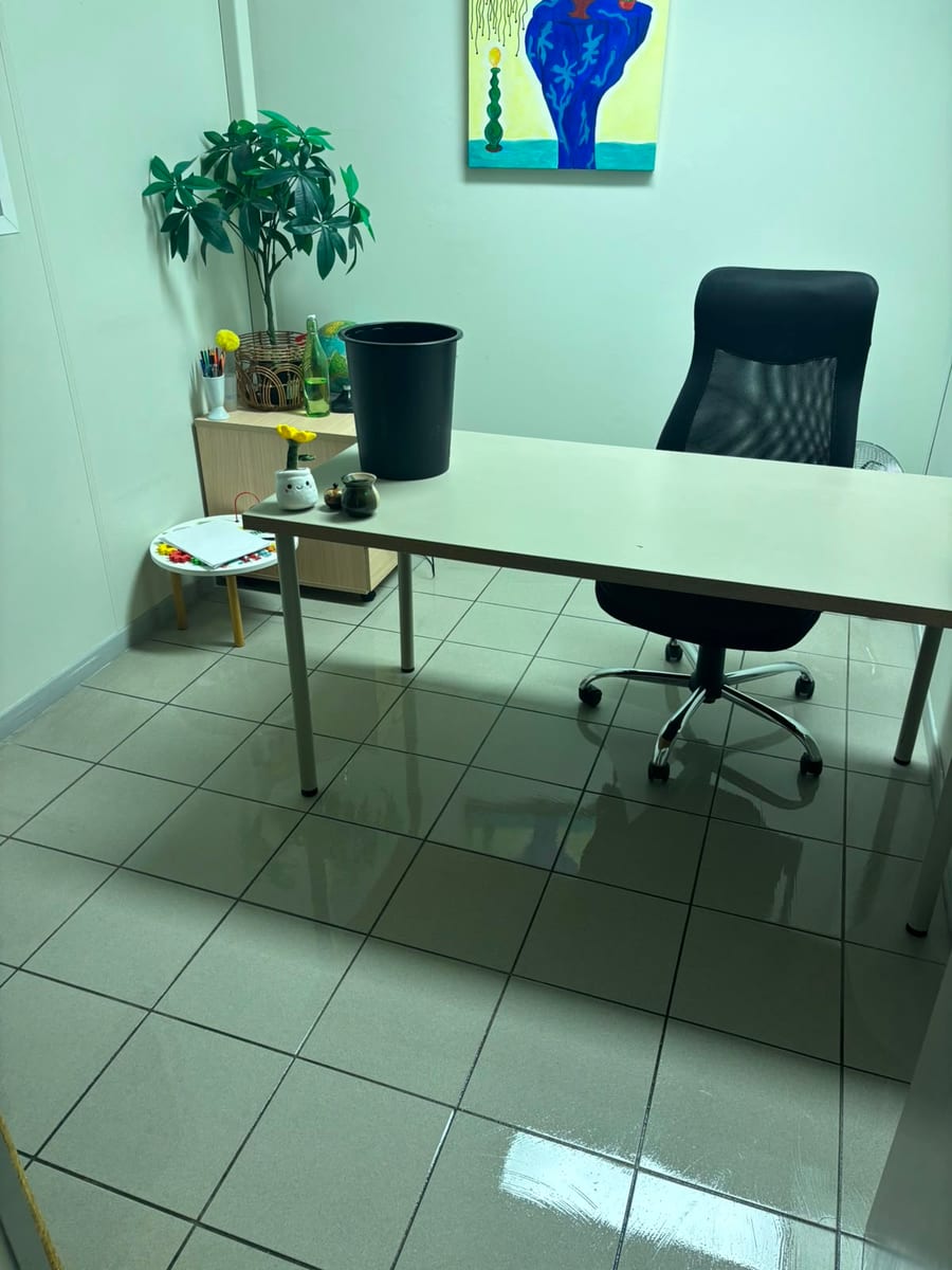 Poste de travail dans un bureau aux murs vert clair, sol carrelé lavé et brillant