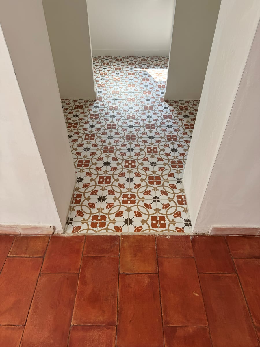 Couloir aux carreaux de ciment à motifs nettoyés, tomettes rouges au premier plan