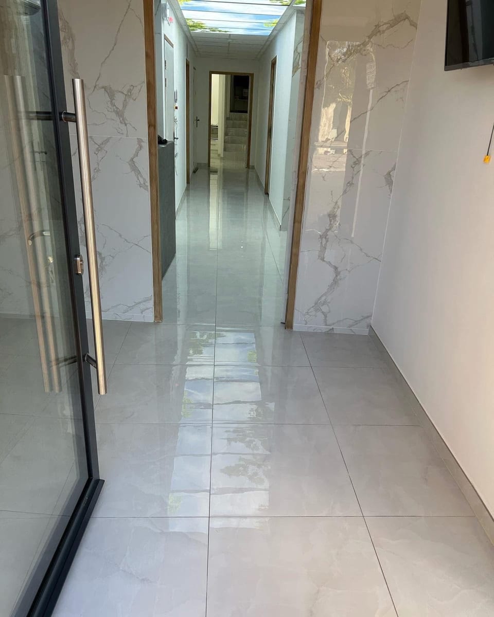 Couloir au carrelage effet marbre blanc lavé, plafond lumineux imprimé ciel et feuillage
