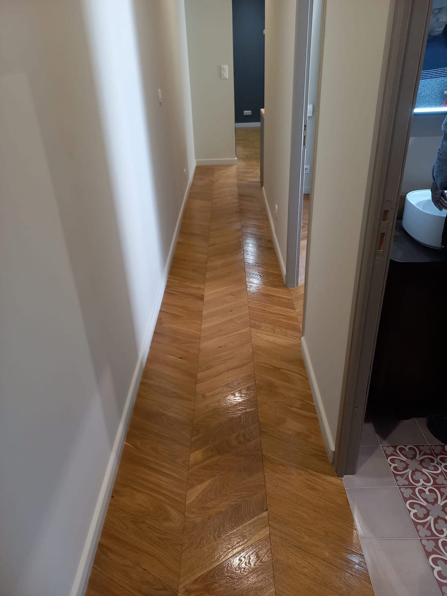 Couloir à parquet en chevrons remis en état, portes ouvertes de part et d’autre