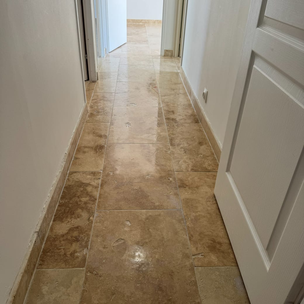 Couloir au sol de travertin beige nettoyé, portes blanches de part et d’autre