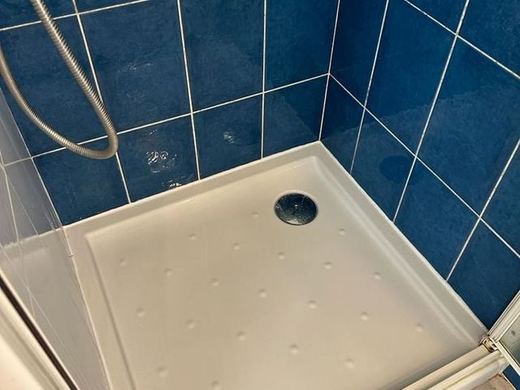 Receveur de douche blanc et faïence bleue nettoyés, bonde et joints repris