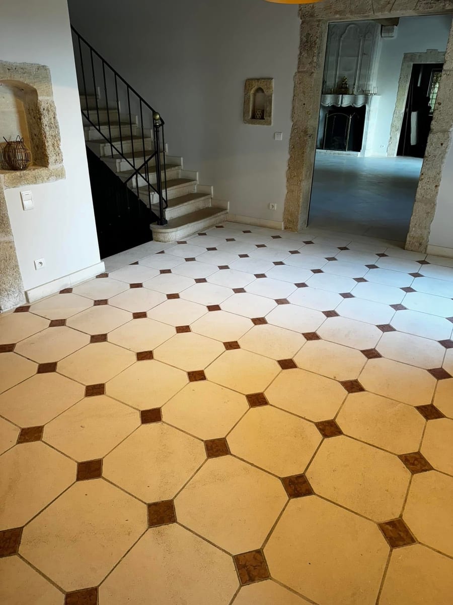 Entrée aux carreaux octogonaux ocre et bruns nettoyés, départ d'escalier au fond