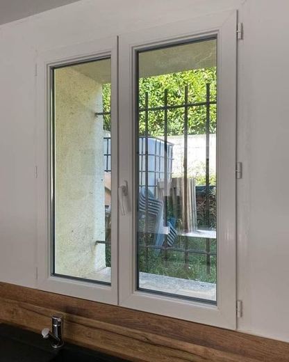 La même fenêtre PVC après nettoyage, dormant blanc net et vitrage transparent sur le jardin