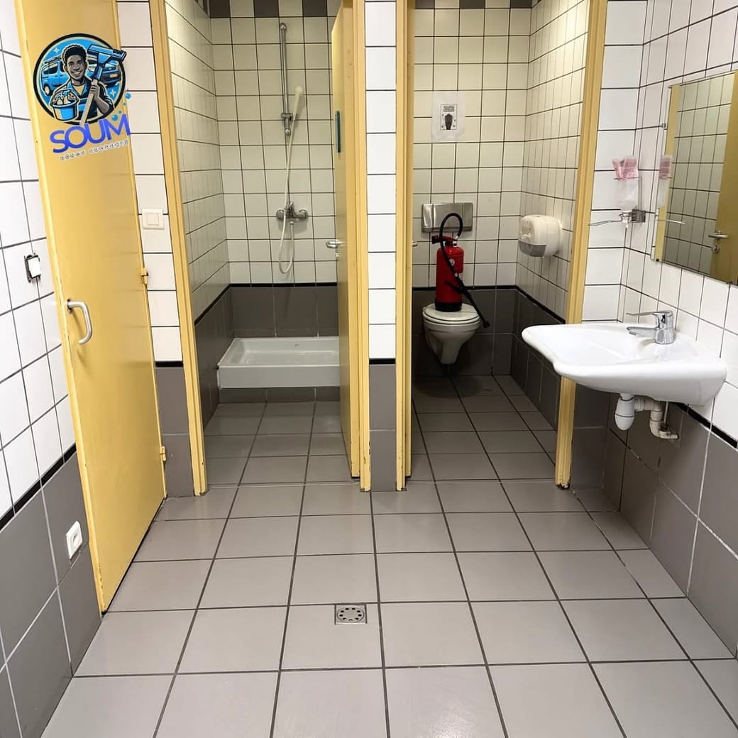 Sanitaires collectifs remis en état, cabines à portes jaunes, lavabo et sol carrelé clair