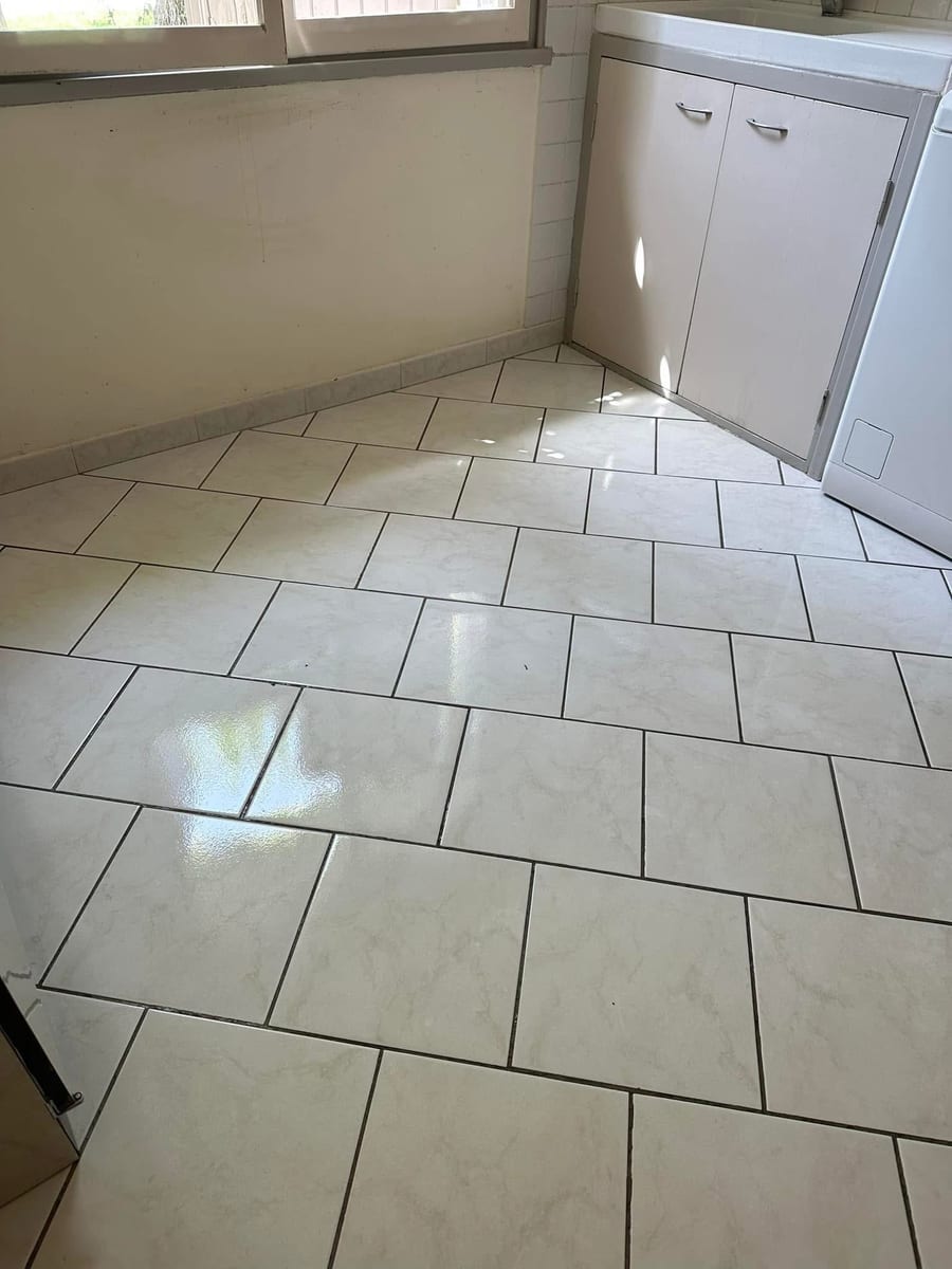 Sol carrelé blanc lavé et brillant devant un meuble bas, angle de pièce