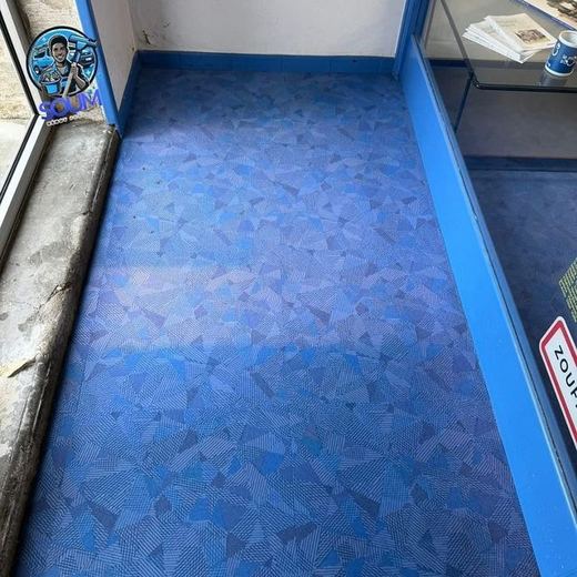 Le même sol souple bleu après décapage, teinte redevenue uniforme jusque le long de la vitrine