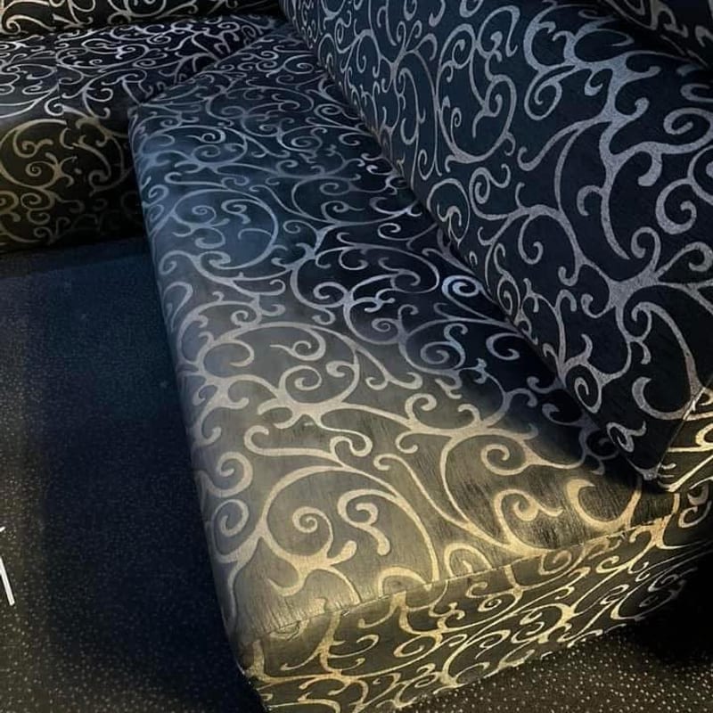 Banquette à motifs dorés sur fond noir, assise marquée d'auréoles claires