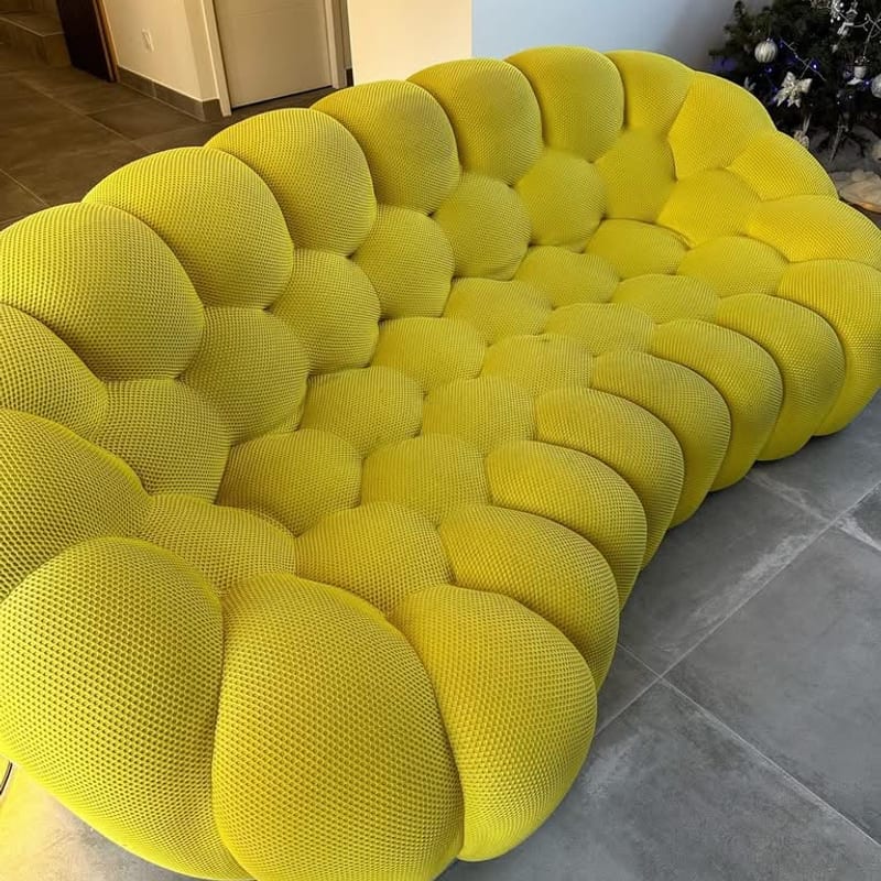 Canapé modulaire en tissu jaune terni, posé sur un carrelage gris