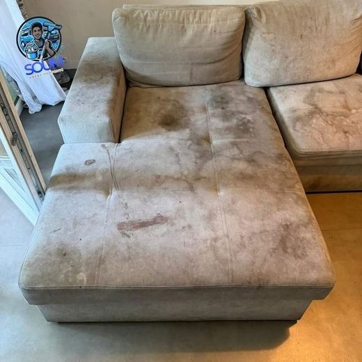 Canapé d'angle beige dont l'assise et la méridienne sont couvertes de larges auréoles brunes