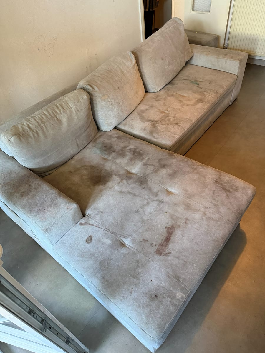 Canapé d'angle en tissu clair couvert de larges taches sombres sur l'assise et la méridienne
