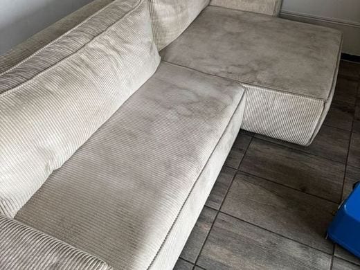 Canapé d'angle en tissu côtelé beige marqué par des traces d'usage avant traitement