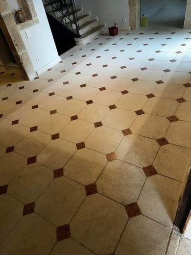 Sol en carreaux octogonaux beiges à cabochons bruns, terni par un voile gris