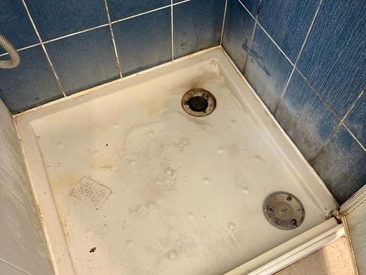 Receveur de douche entartré et joints de faïence bleue noircis avant intervention