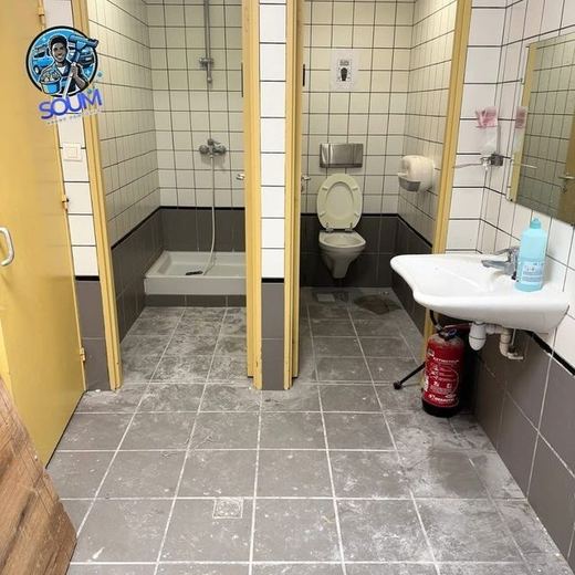 Douches et WC collectifs dont le sol gris est maculé de traînées blanchâtres