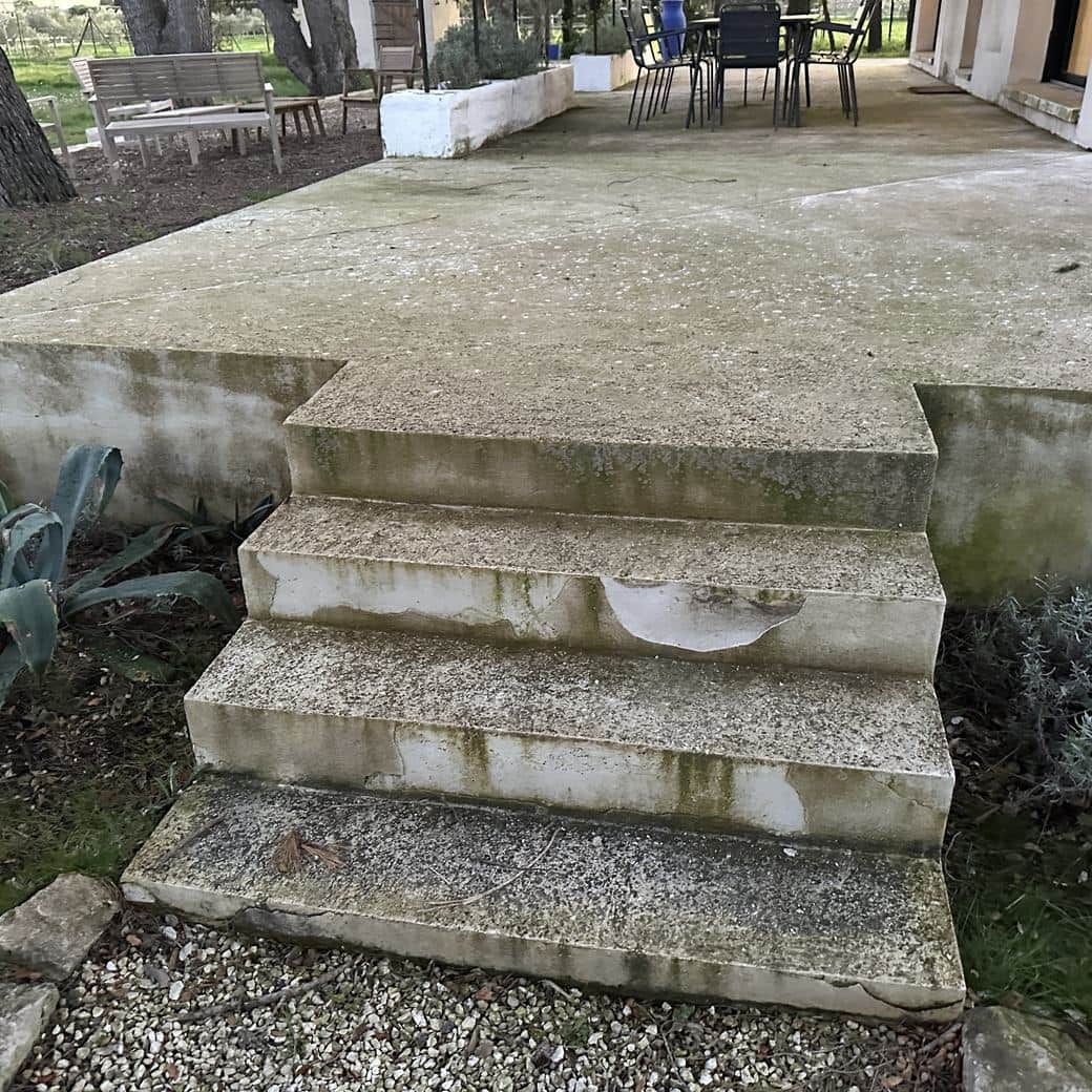 Escalier extérieur en pierre claire encrassé et verdi, marches noircies par le temps