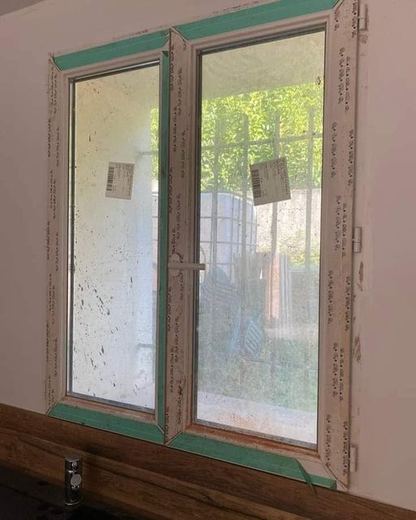 Fenêtre PVC à deux battants dont le dormant est maculé de traces vertes et de salissures