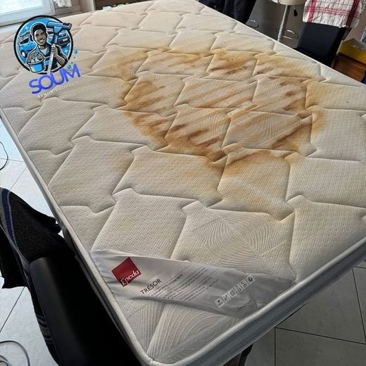 Matelas blanc posé sur la tranche, marqué en son centre d'une large auréole brune