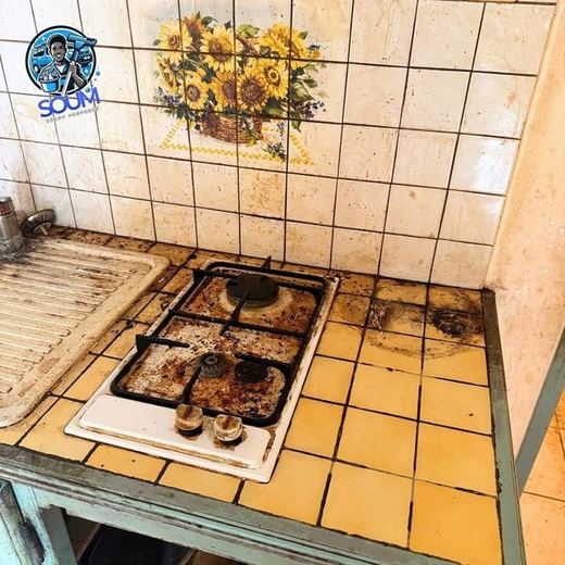 Plaque de cuisson au gaz encroûtée de graisse brune sur un plan de travail carrelé jaune