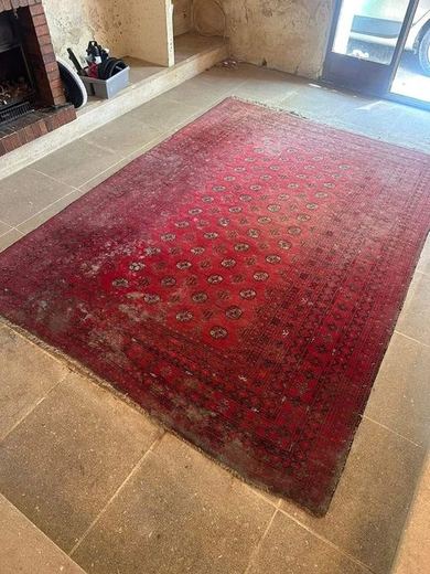 Tapis persan rouge à médaillons voilé de gris, posé sur un sol de pierre claire