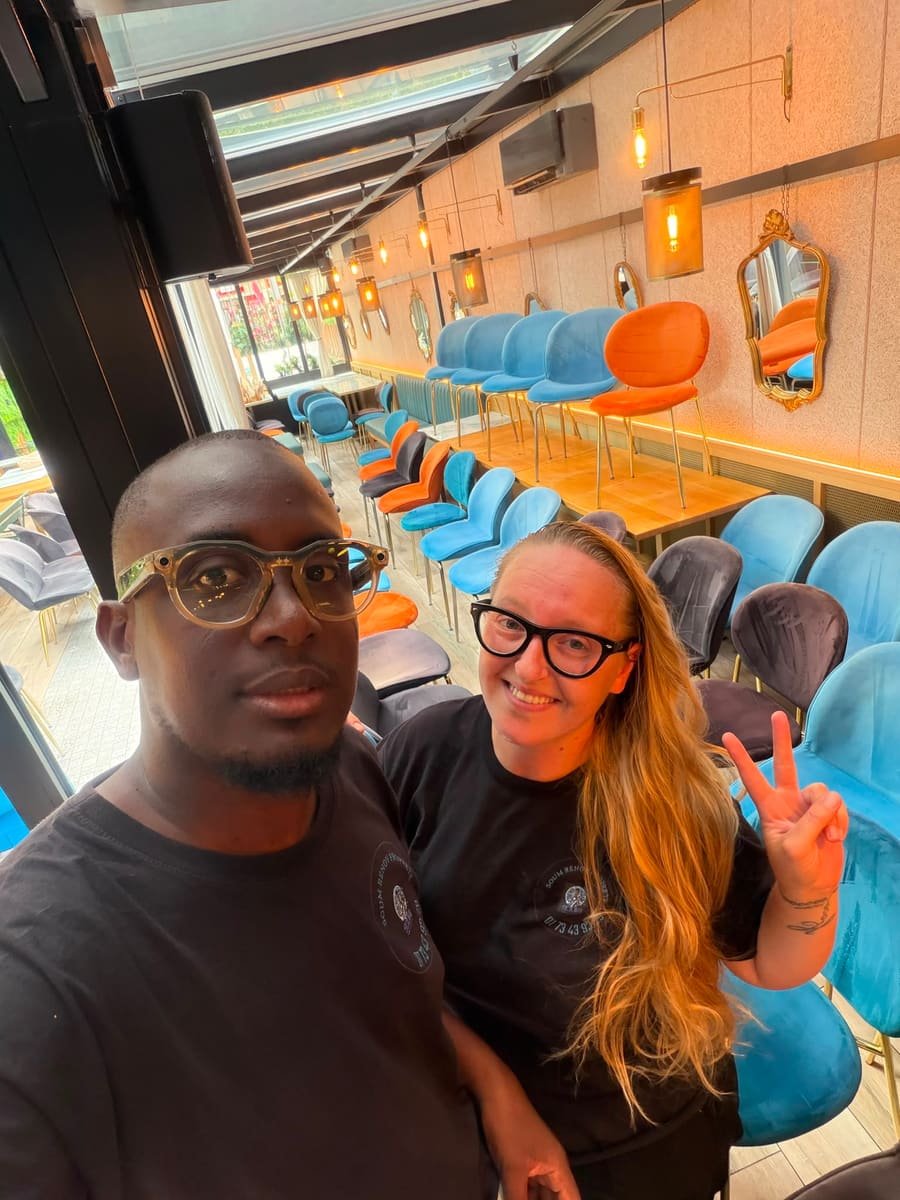 Soum et Cassandra en t-shirt Soum Rénov Propreté, selfie dans un bar aux chaises de velours colorées