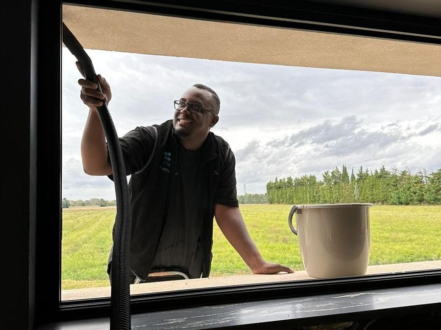 Soum nettoie une fenêtre depuis l'extérieur, vu à travers le vitrage